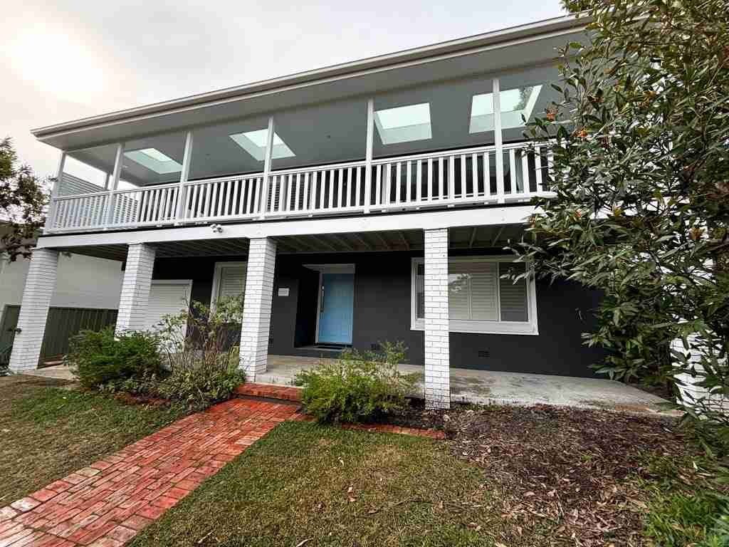 Two-story house with white porch railing, blue front door, and red brick walkway.