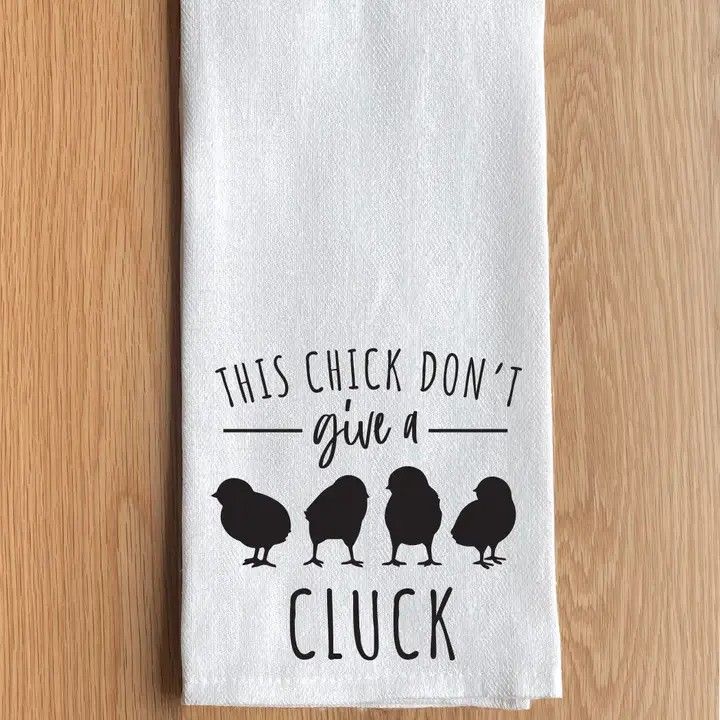 White towel on wood table with chicken graphic and text, “This chick don’t give a cluck.”