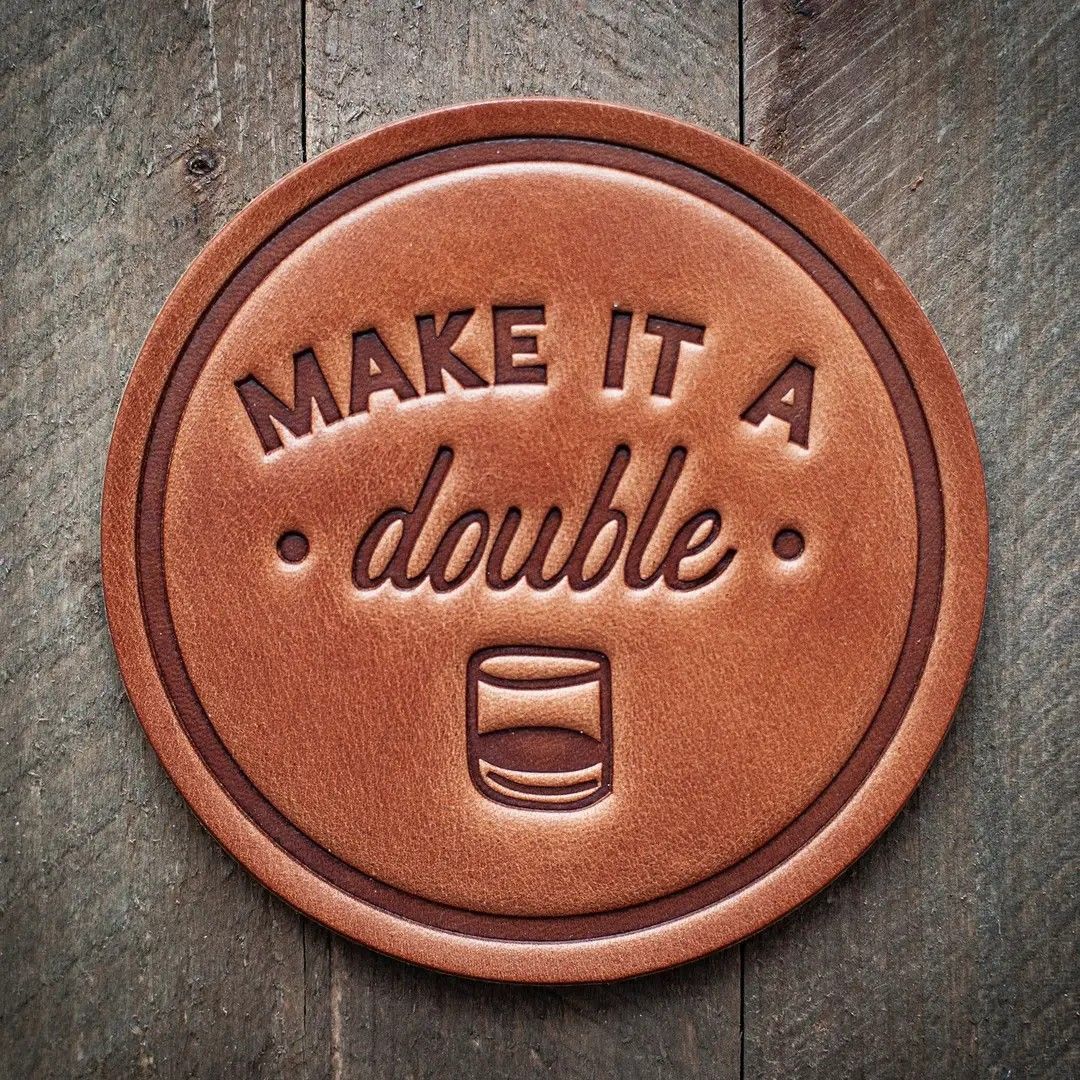 Circular brown leather patch on wood reading “MAKE IT A double” with a small cup icon.