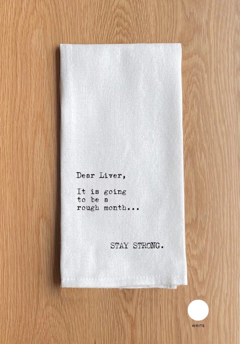 Small white folded note on a wooden surface with a handwritten message.