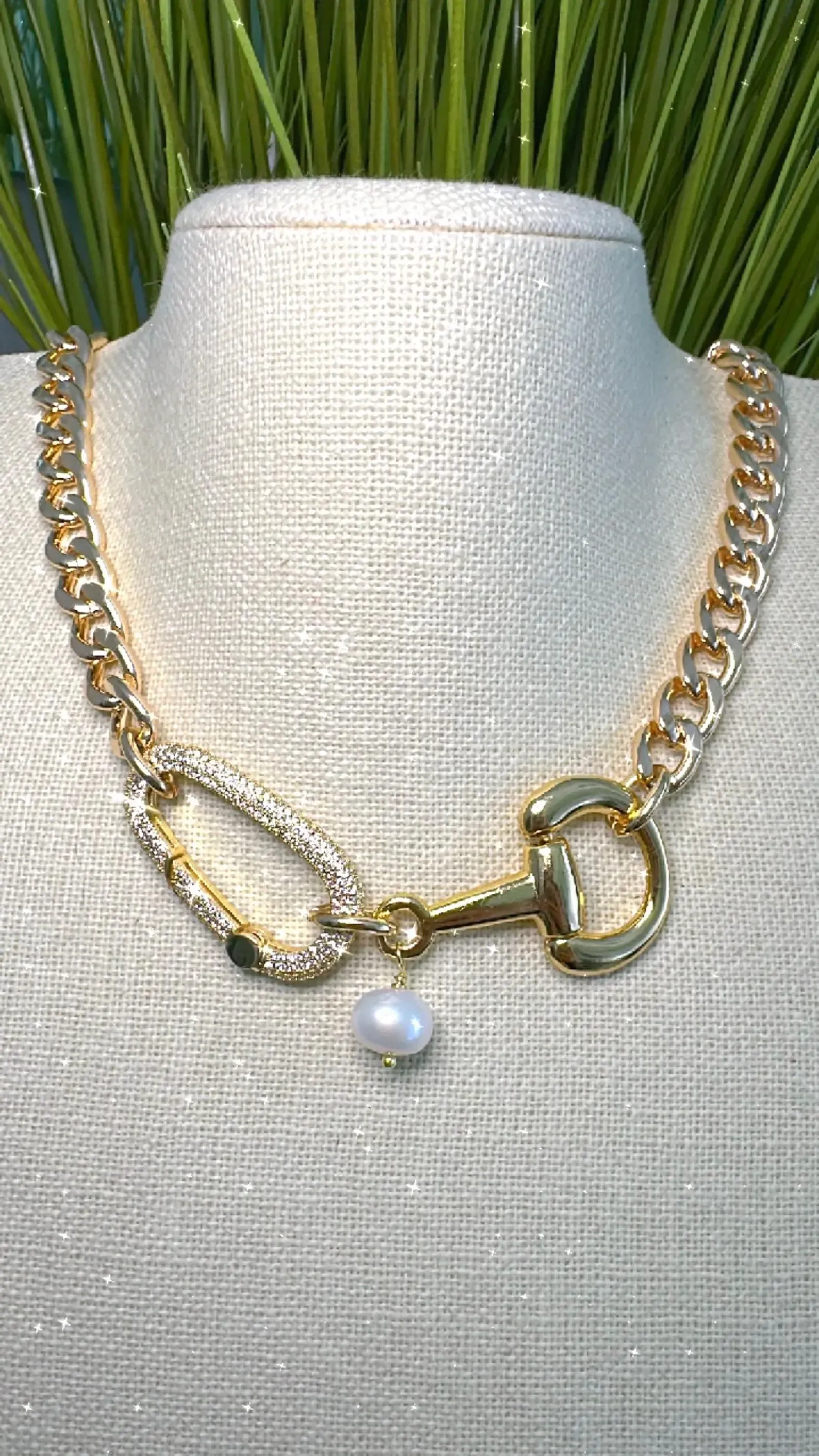 Gold chain necklace with large links and a pearl pendant on a white display bust