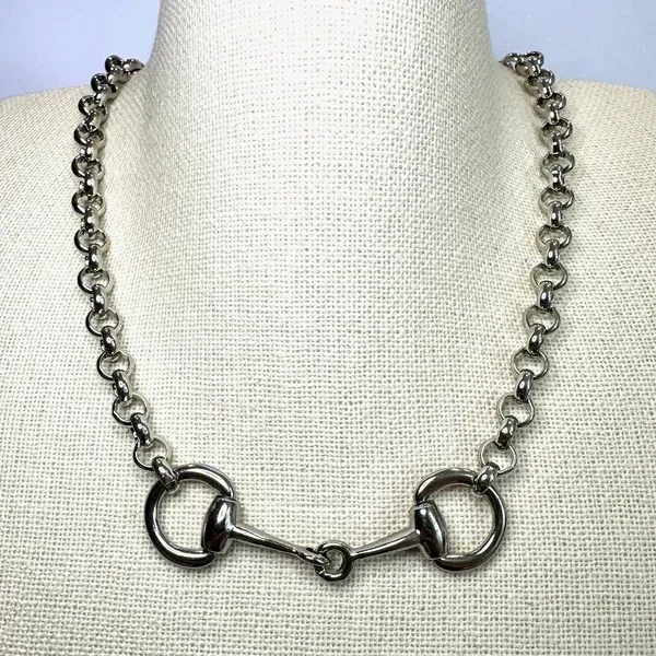 Silver bead chain necklace with large circular clasp on a display bust
