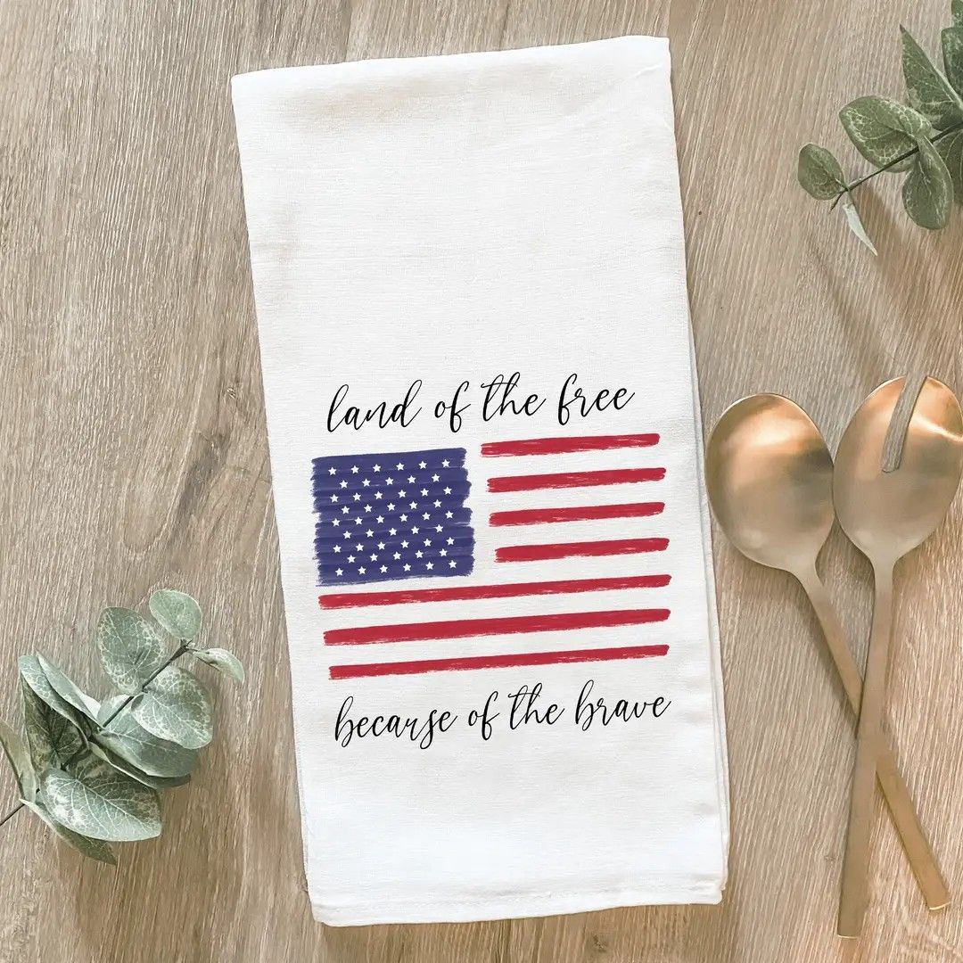 Patriotic towel with American flag and text “land of the free, home of the brave” on a wooden table