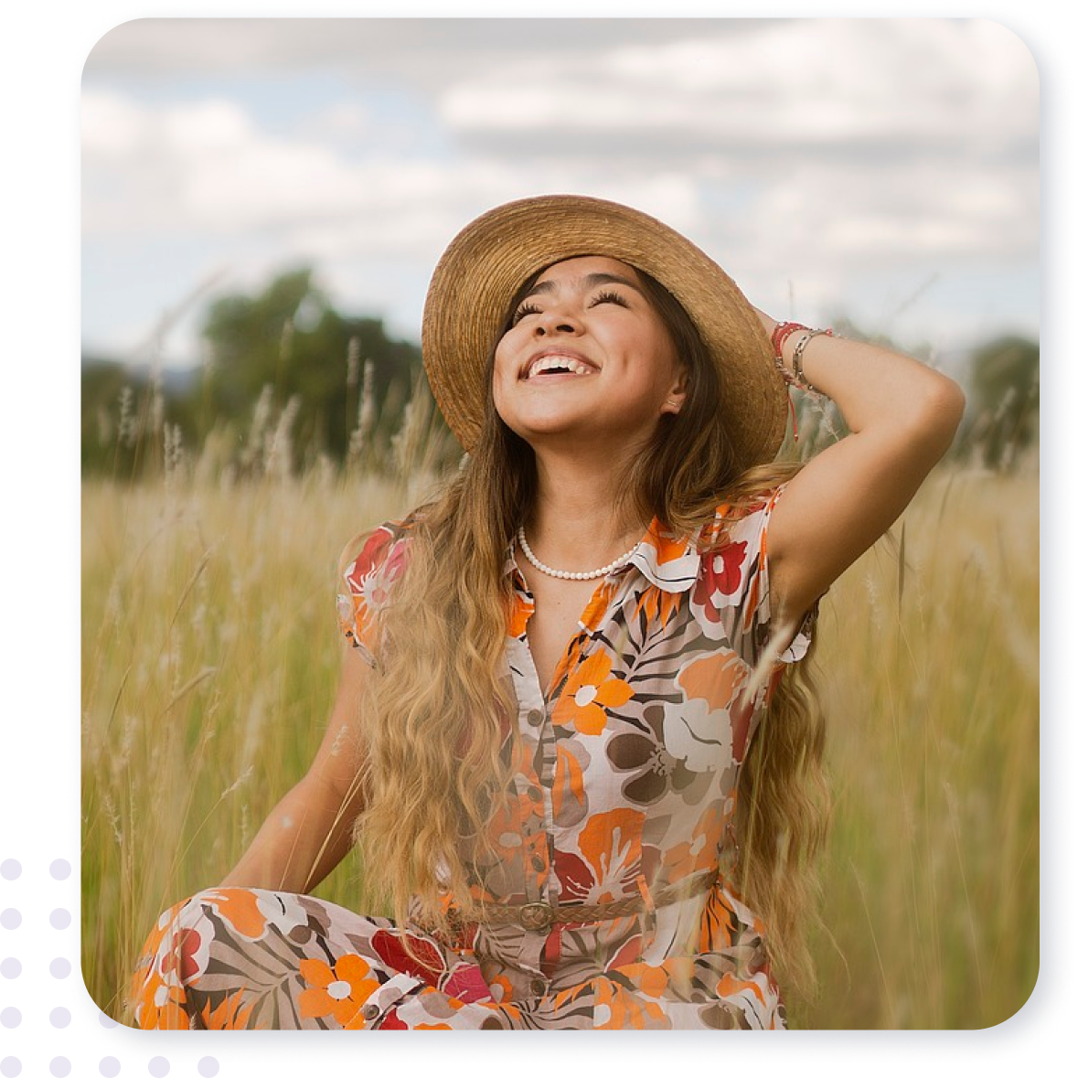 A woman wearing a straw hat is sitting in a field