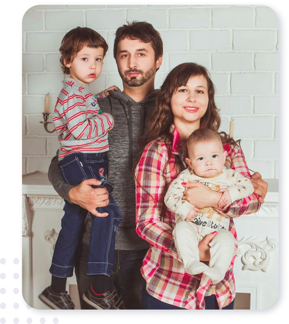 A family is posing for a picture in front of a fireplace.