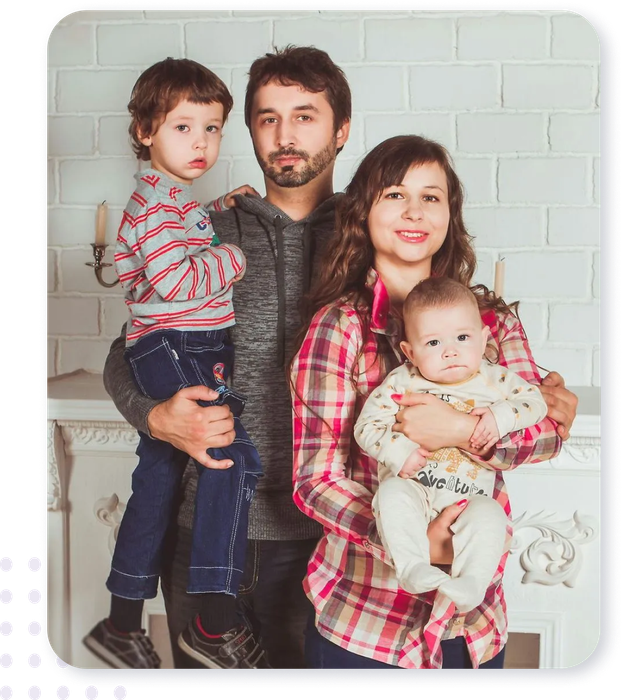 A family is posing for a picture in front of a fireplace.