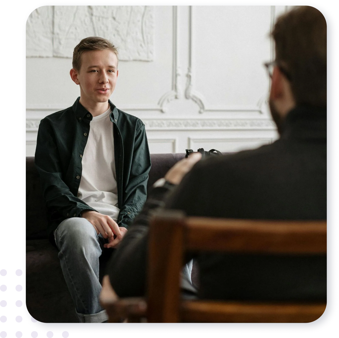 A man is sitting on a couch talking to another man.