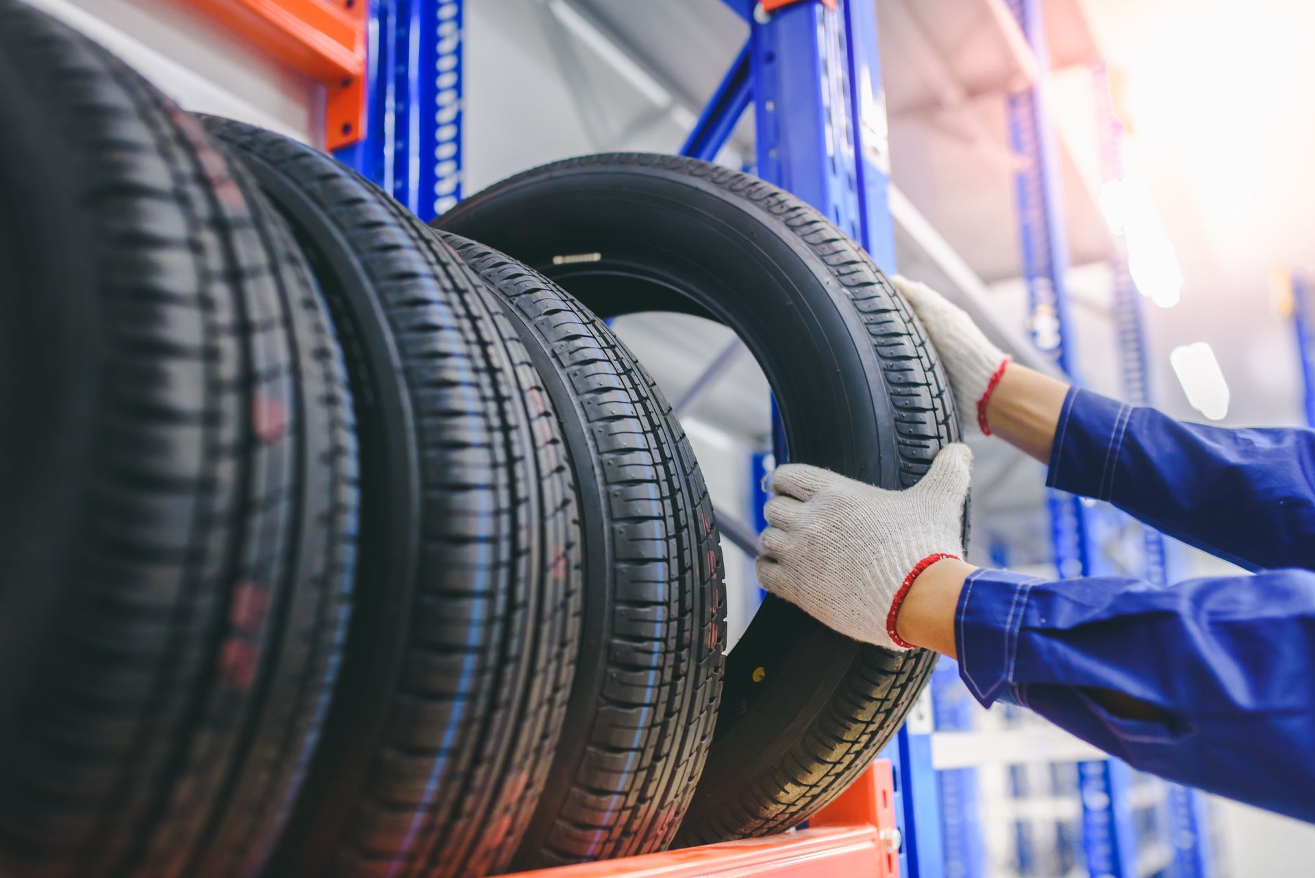 A man is taking a tire from a rack.