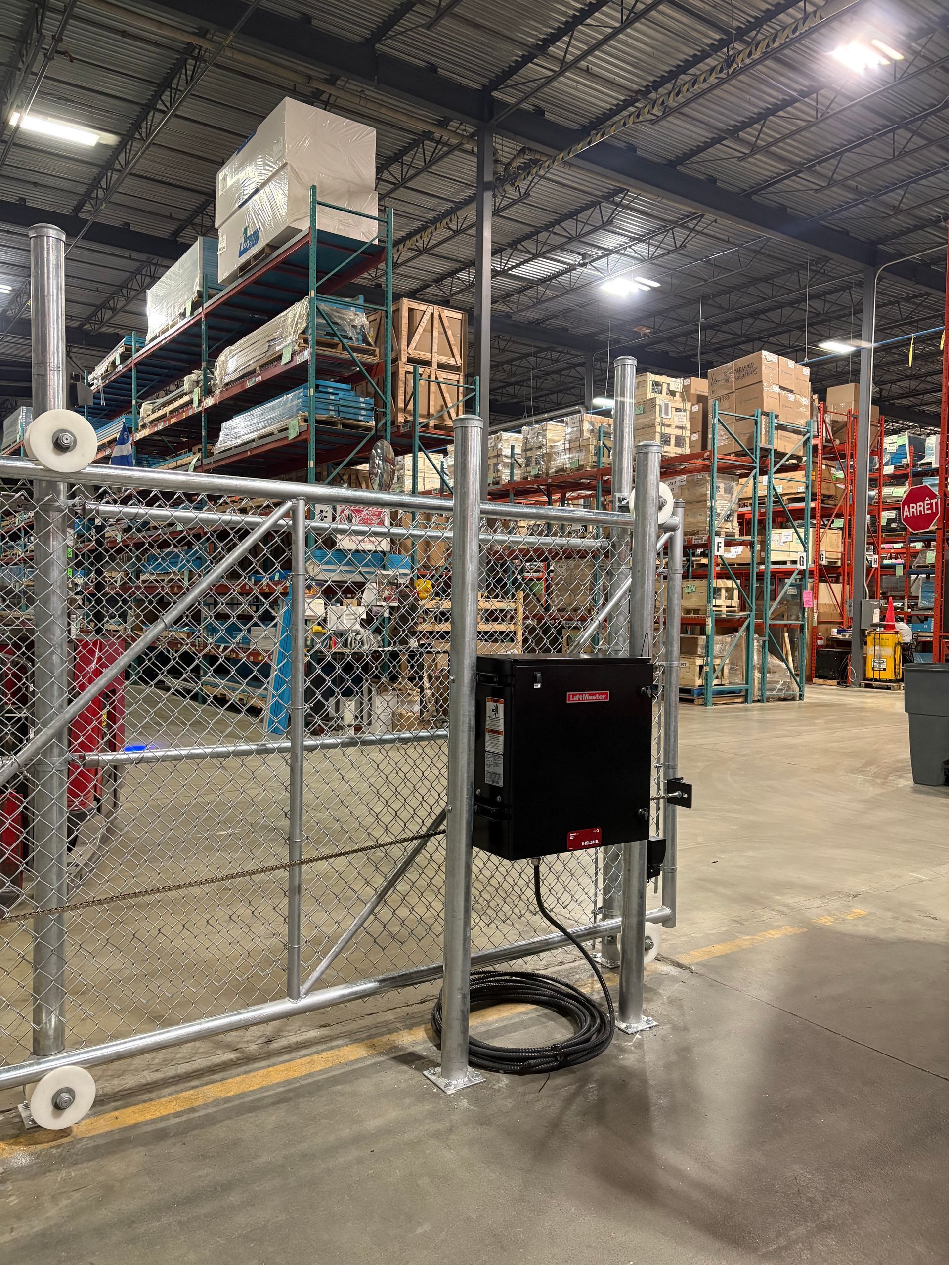 Un entrepôt avec une clôture à mailles losangées et un portail.