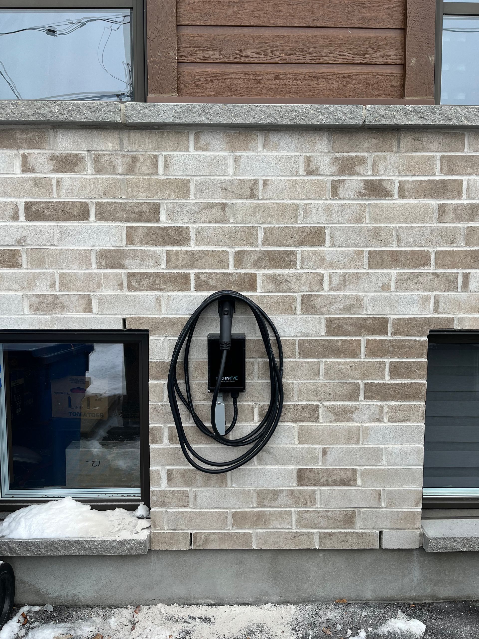 Un mur de briques avec un cordon d'alimentation suspendu.