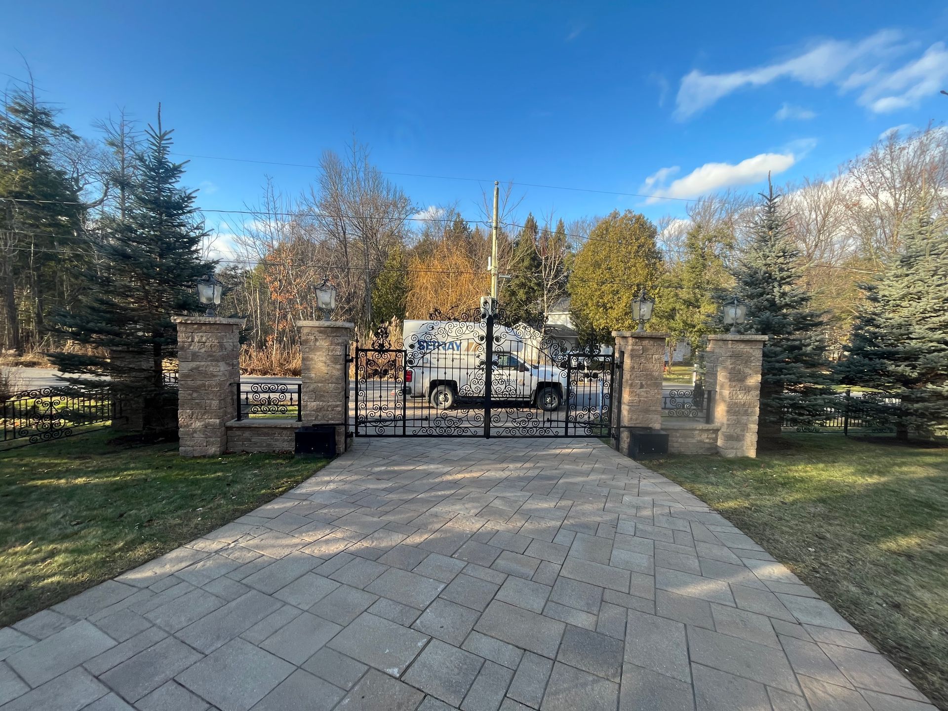 Une camionnette blanche est garée devant un portail dans une allée.
