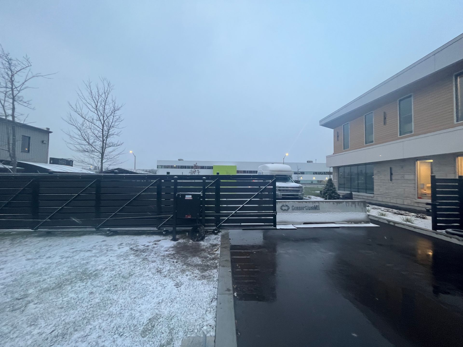 Une allée enneigée avec une clôture et un bâtiment en arrière-plan.