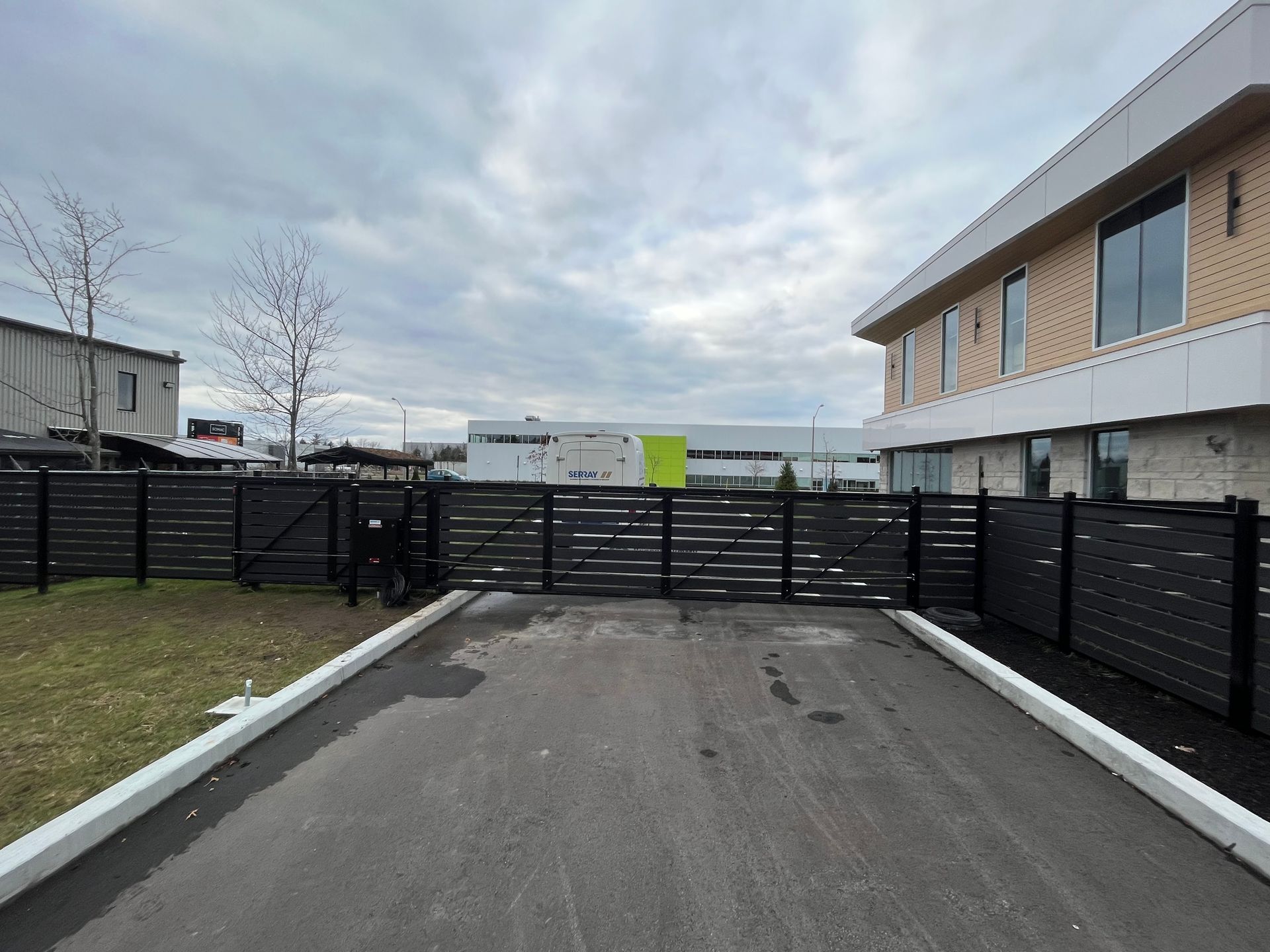 Une clôture noire entoure une allée menant à un bâtiment.