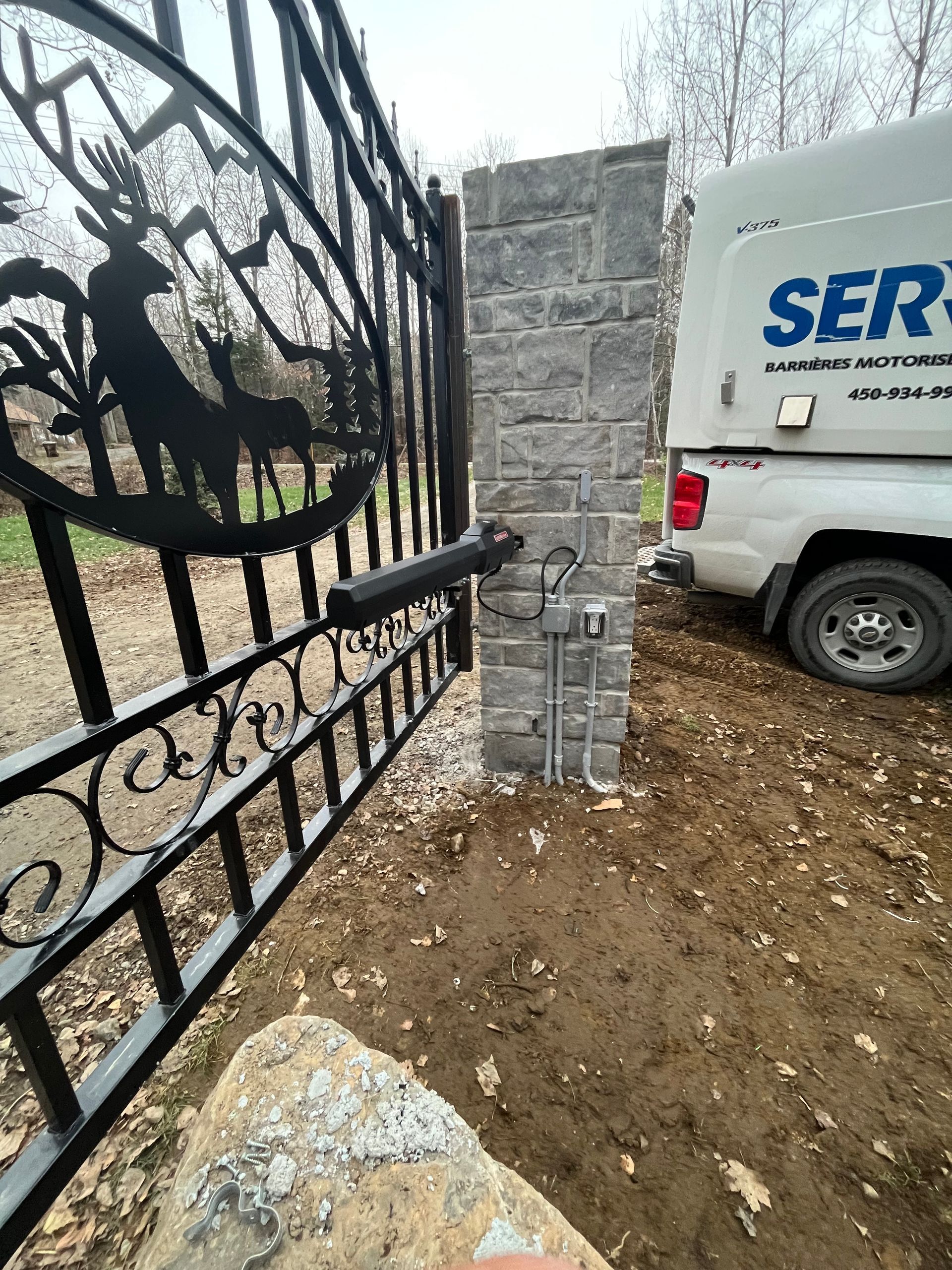 Un camion blanc est garé à côté d'un portail en fer forgé.