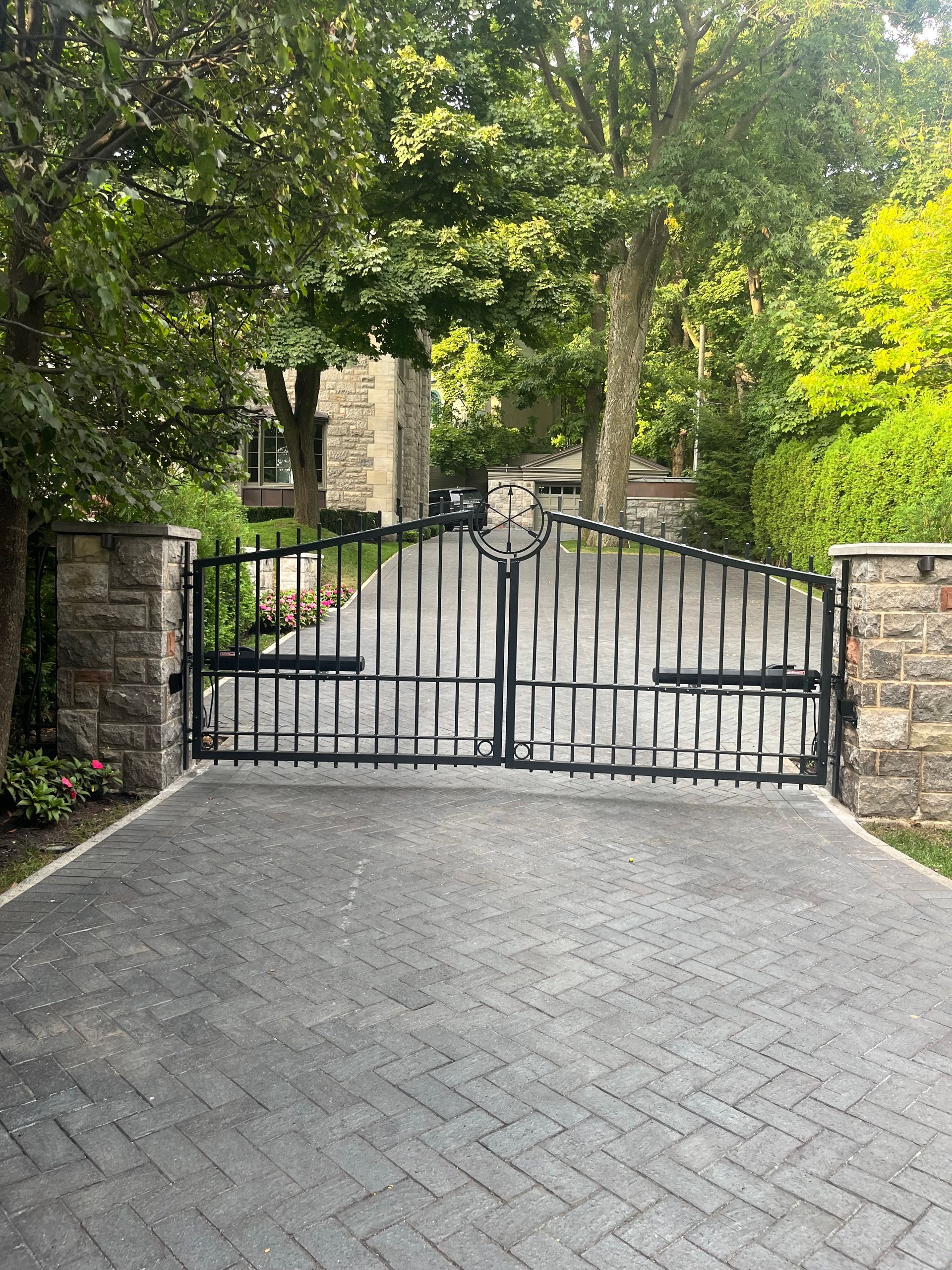 Une allée en briques avec un portail en fer forgé menant à une maison.