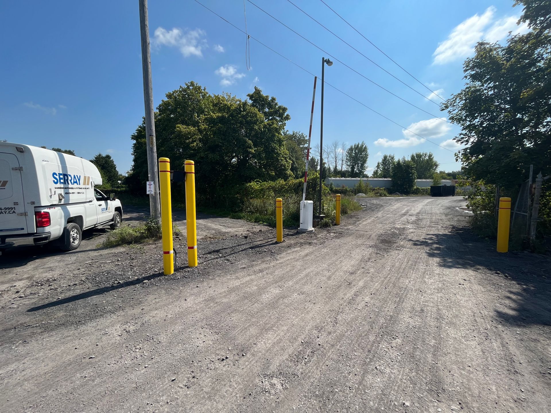 Une camionnette blanche est garée sur le bord d'un chemin de terre.