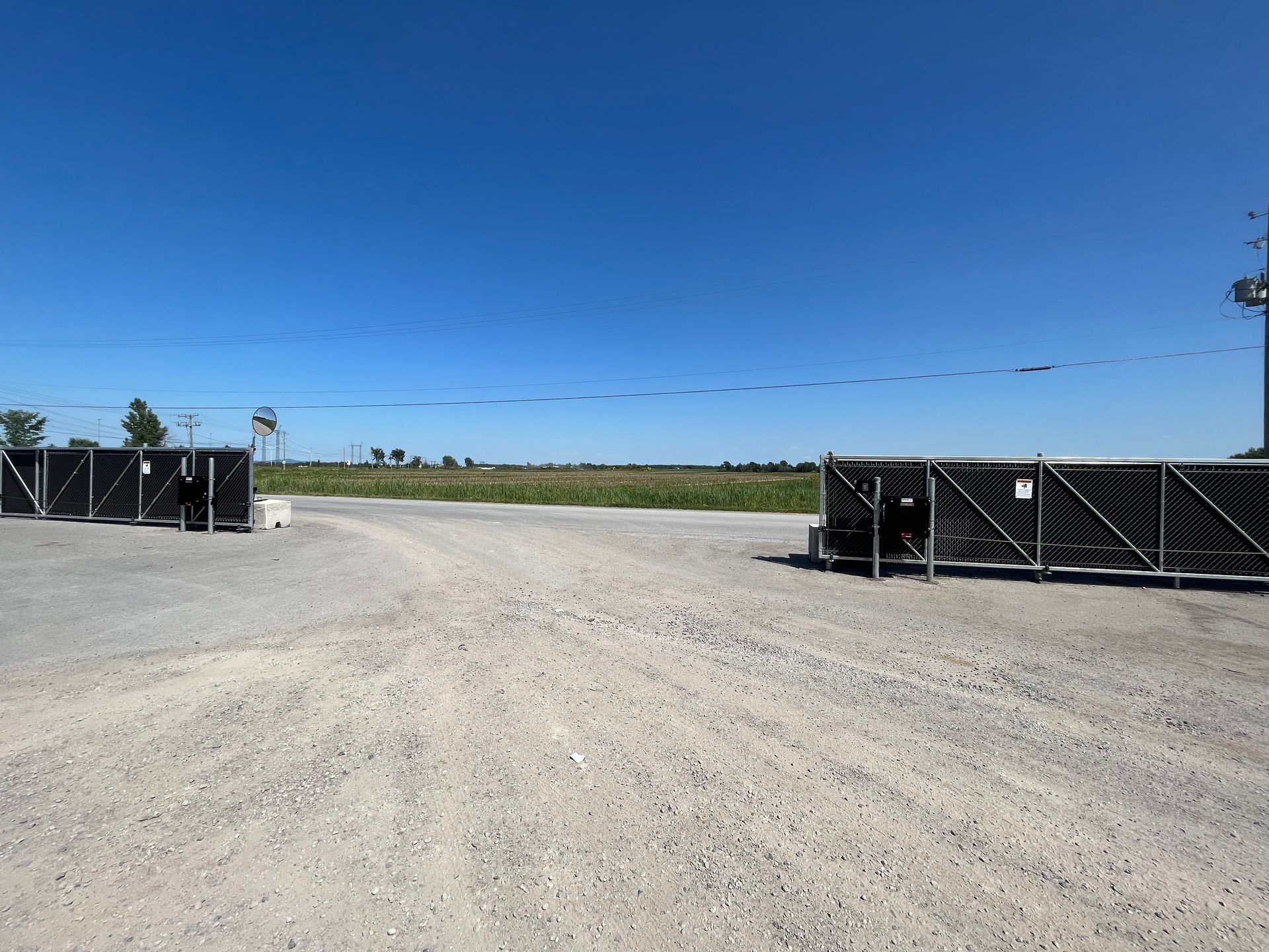 Une rangée de conteneurs noirs se trouve sur un terrain en gravier