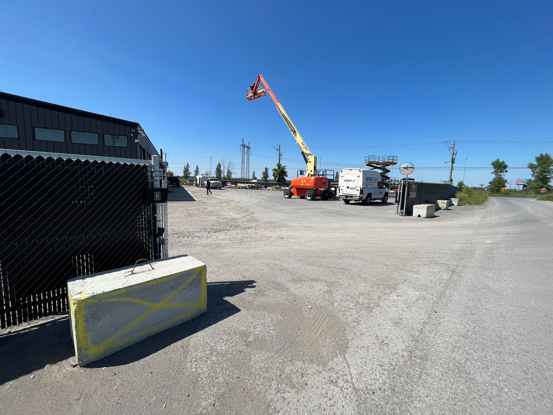 Une grue est assise sur un parking à côté d'une clôture grillagée.