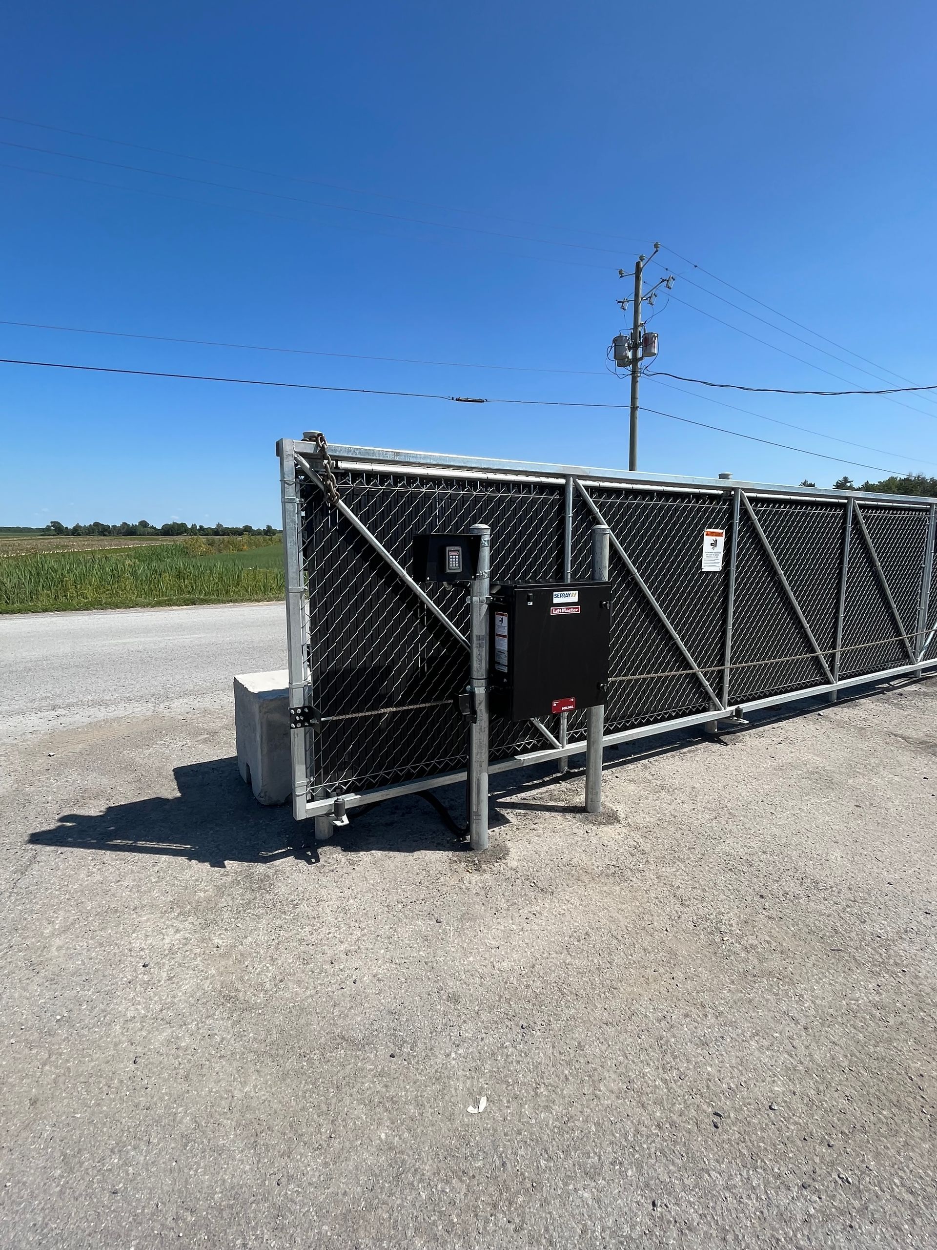 Une grande clôture noire se trouve au milieu d'un chemin de gravier.