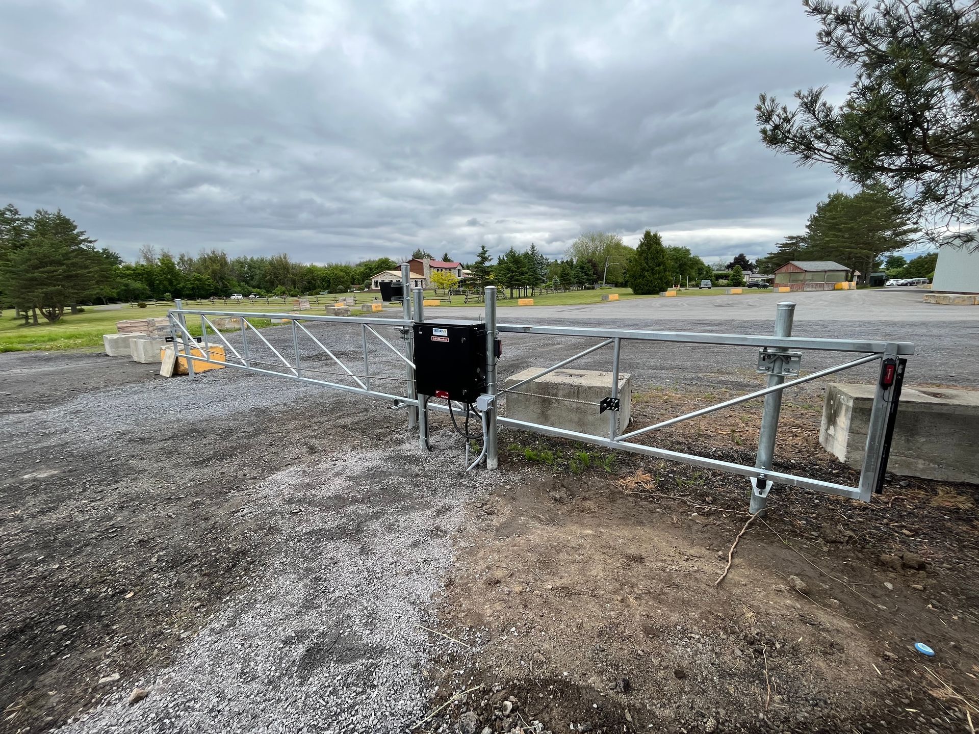 Une porte en métal se trouve au milieu d'un chemin de gravier.