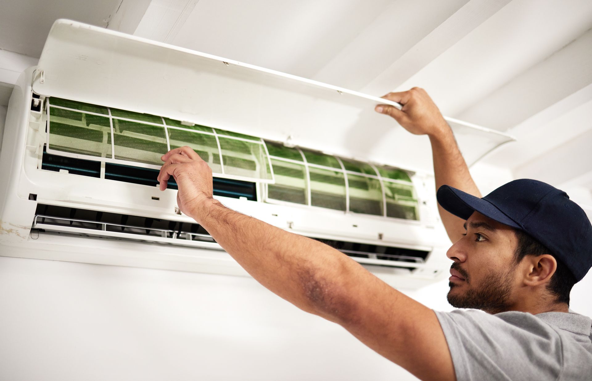 Technician cleaning a wall-mounted air conditioner with the cover open
