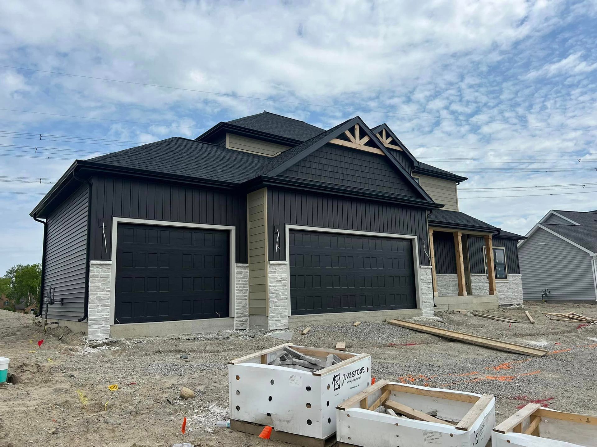 A large house with two garage doors is being built in a residential area.