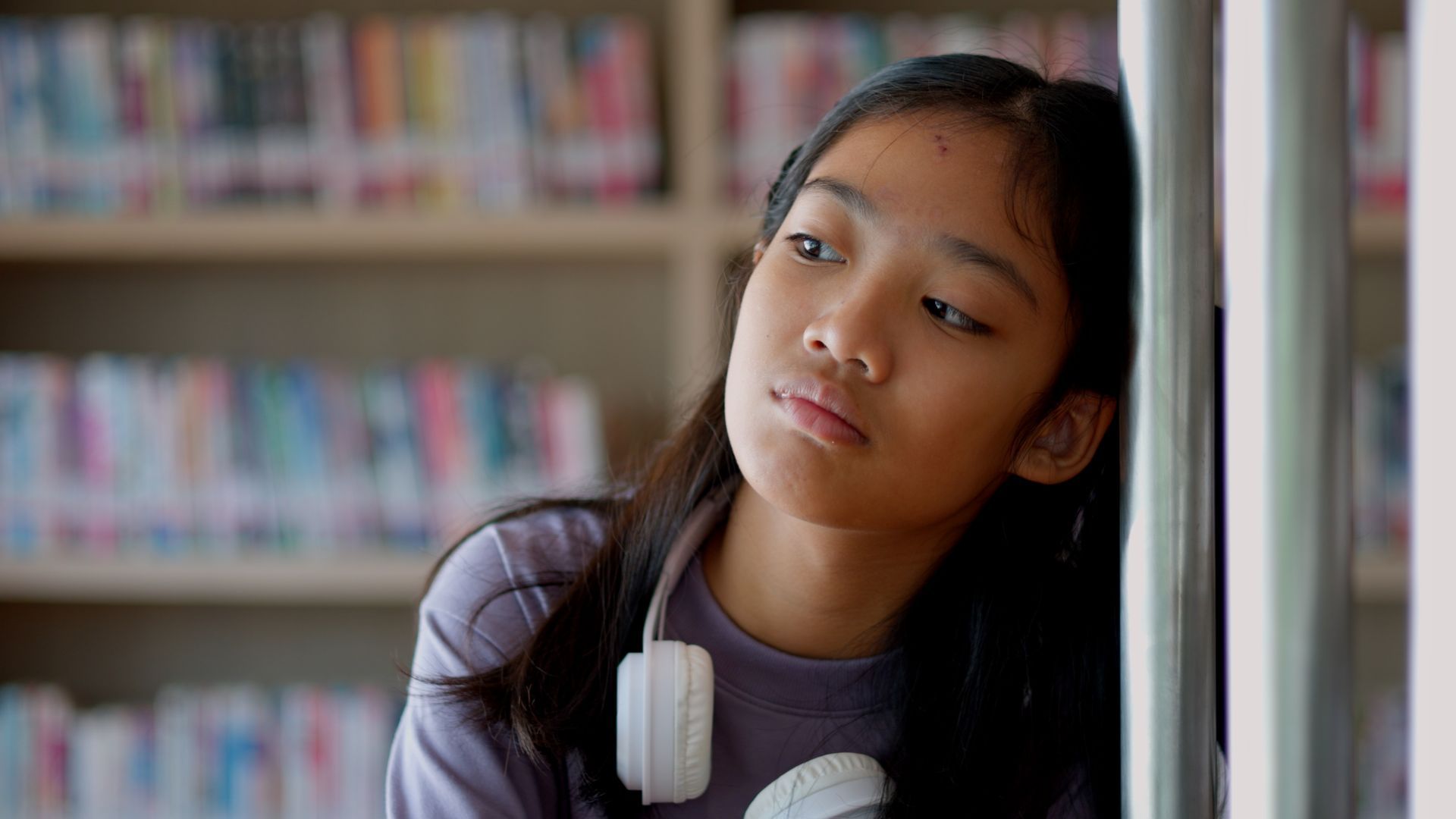 A woman is sitting in front of a laptop computer with her hands on her head.
