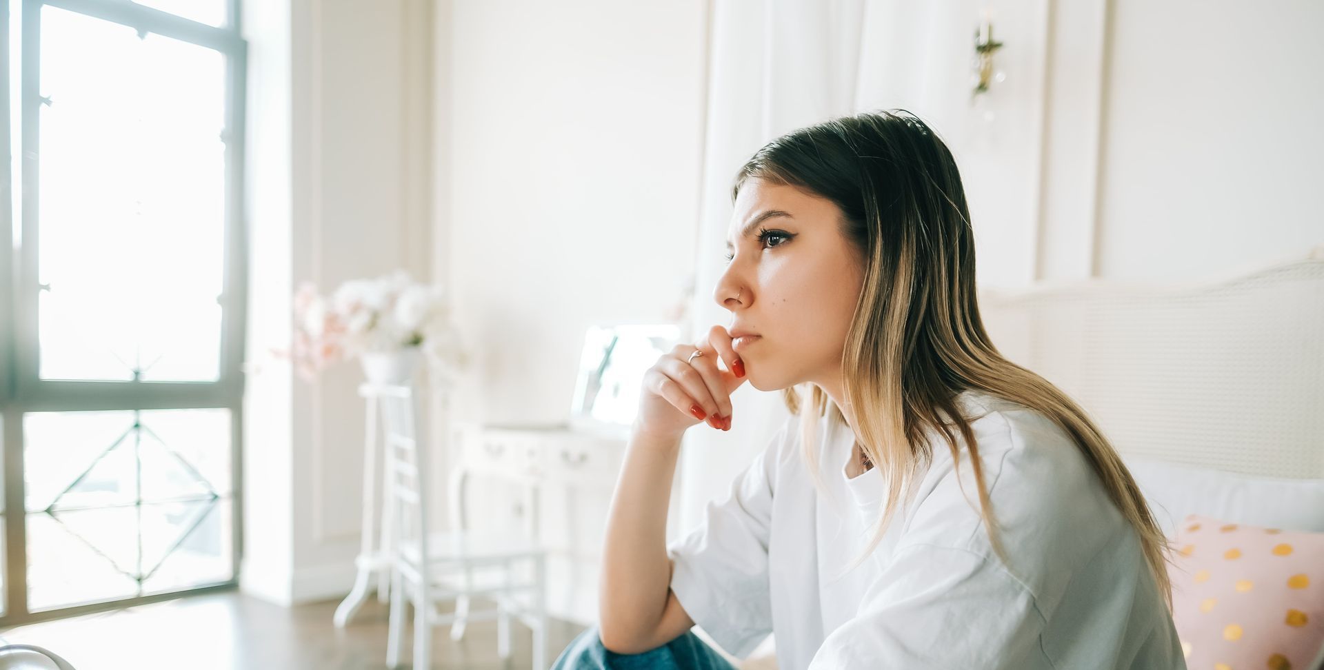 A woman sitting on her bed contemplating