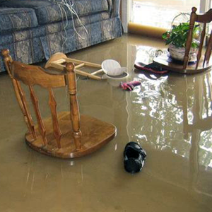 A wooden rocking chair is sitting in a flooded living room.