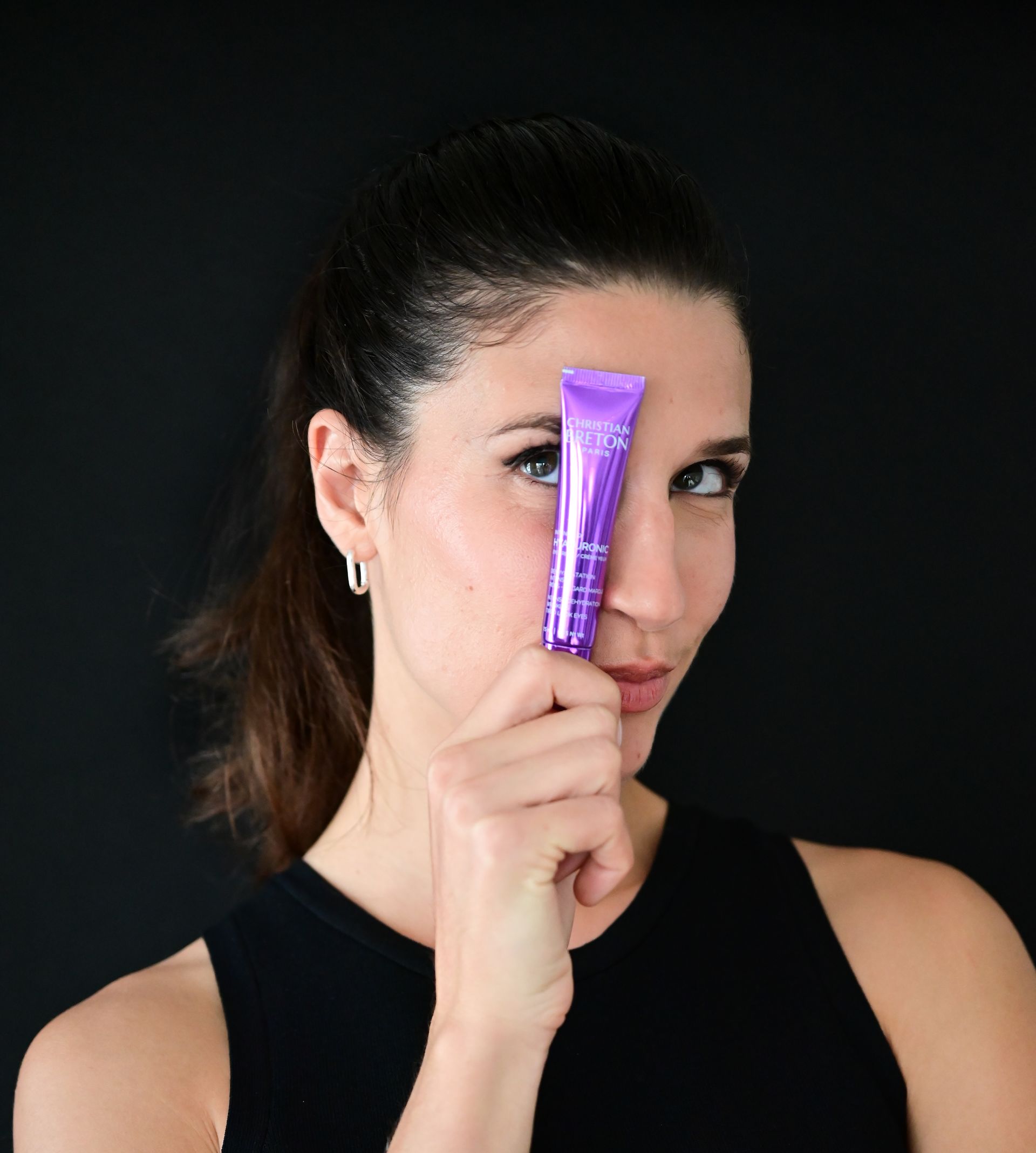 Una mujer sostiene un tubo morado frente a su cara.