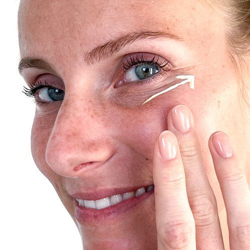 Una mujer se aplica una crema en la cara.