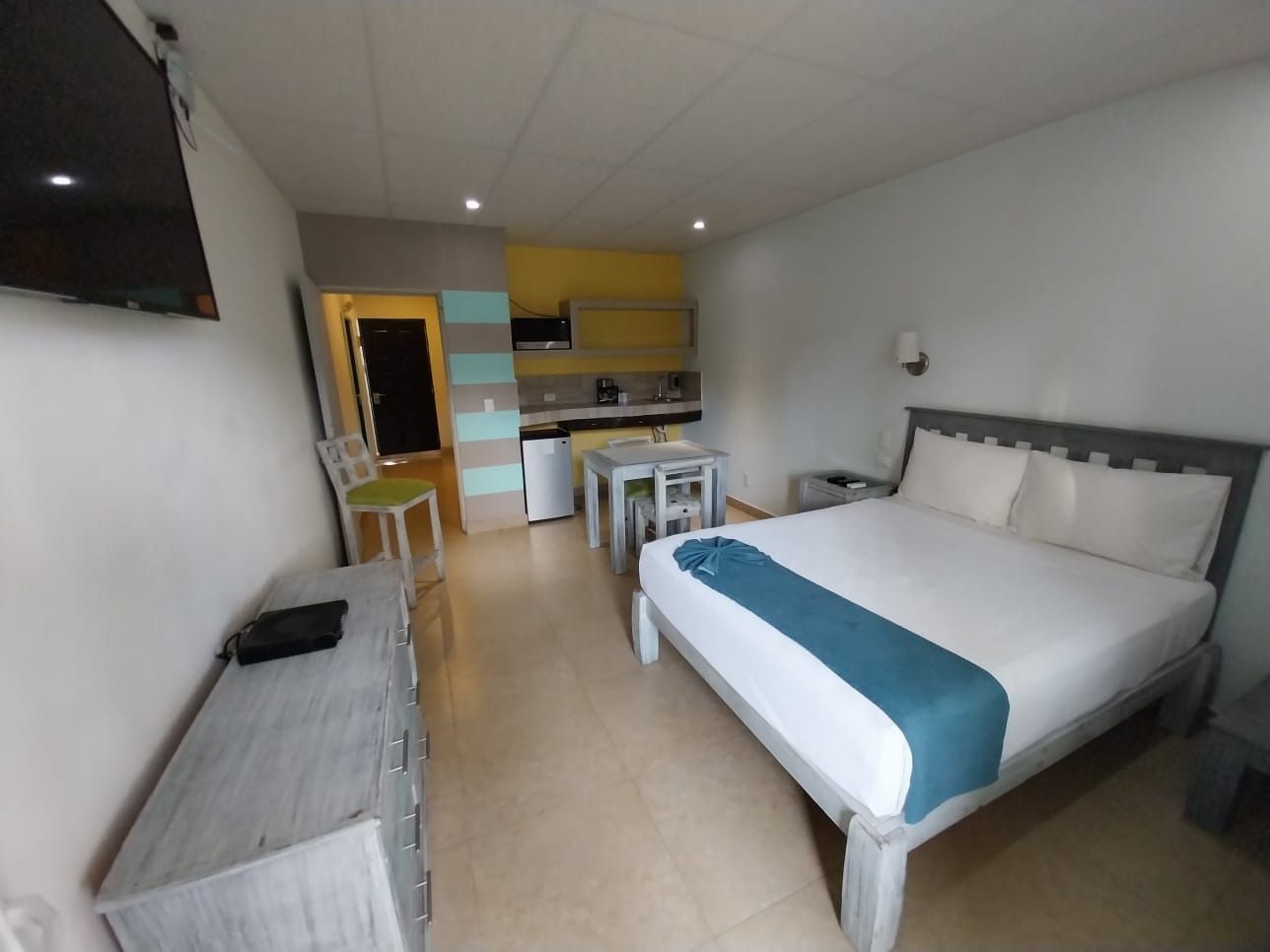 A hotel room with a king size bed and a flat screen tv