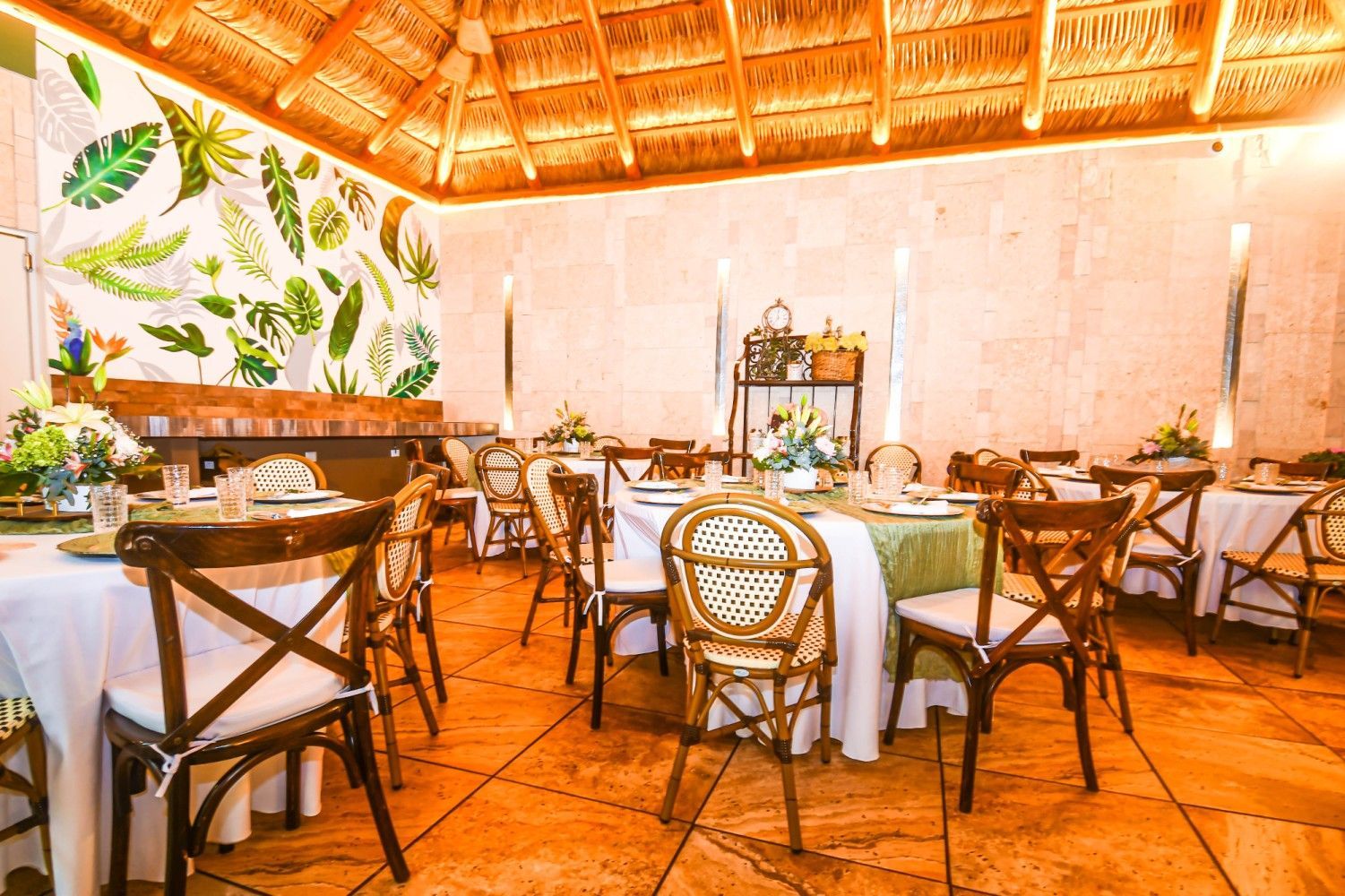 A restaurant filled with tables and chairs and a thatched roof.
