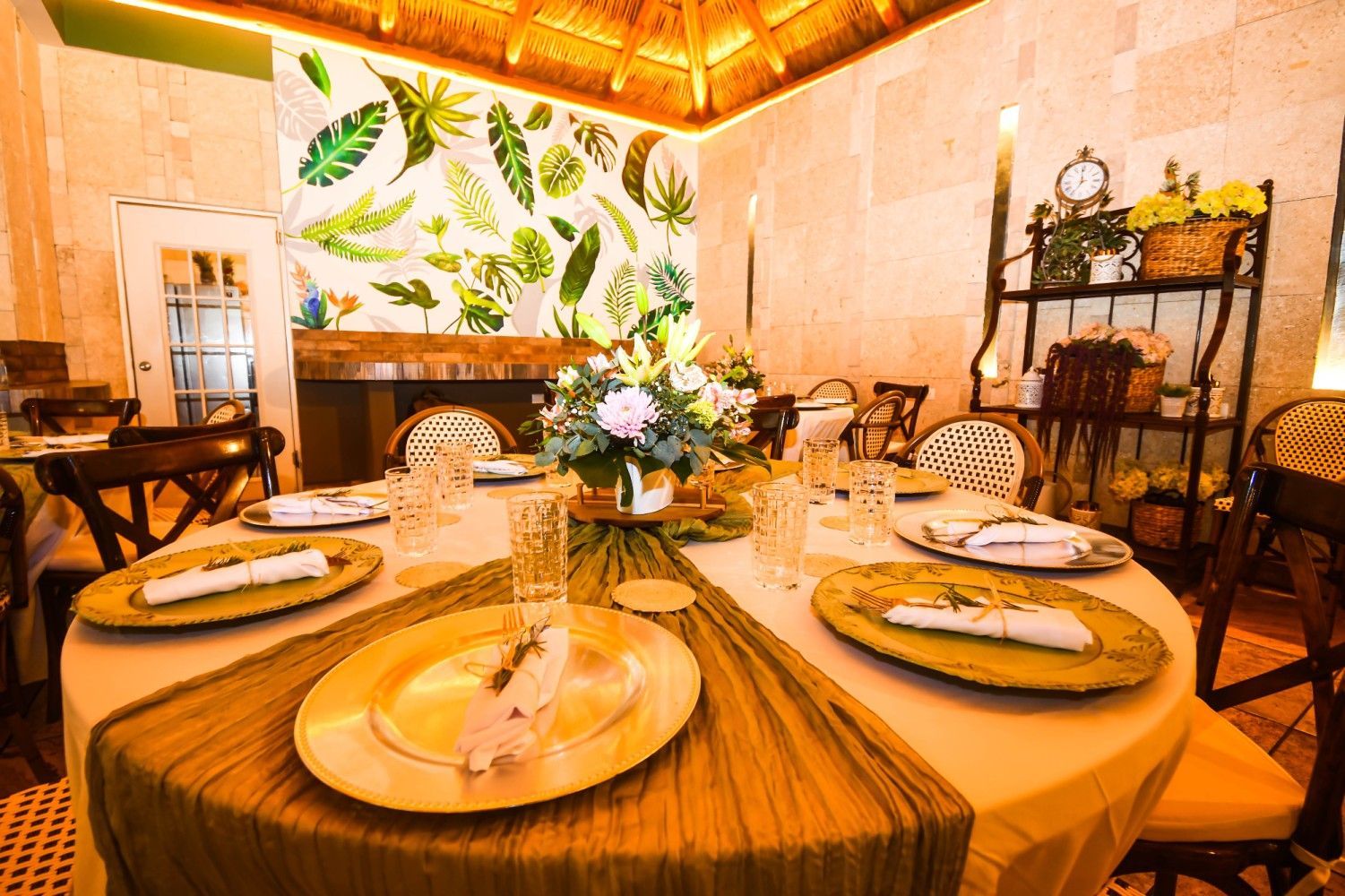 A table with plates , glasses , napkins and a vase of flowers on it.