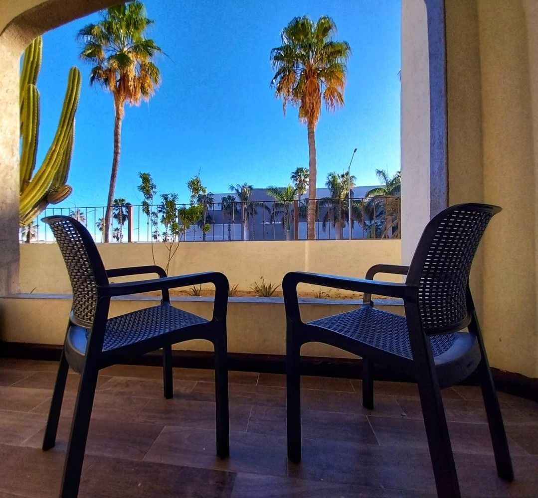 Two chairs on a balcony with palm trees in the background