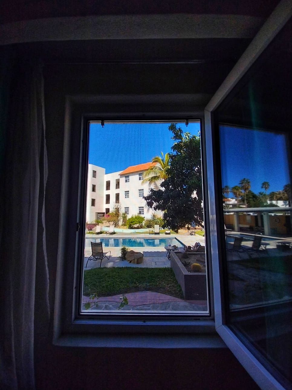 An open window with a view of a building and a pool