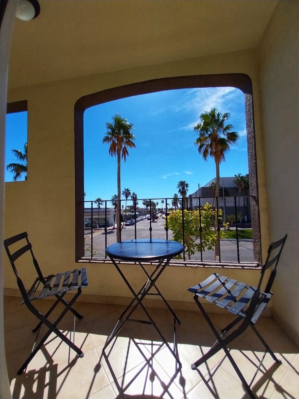 A balcony with a table and chairs and a view of palm trees