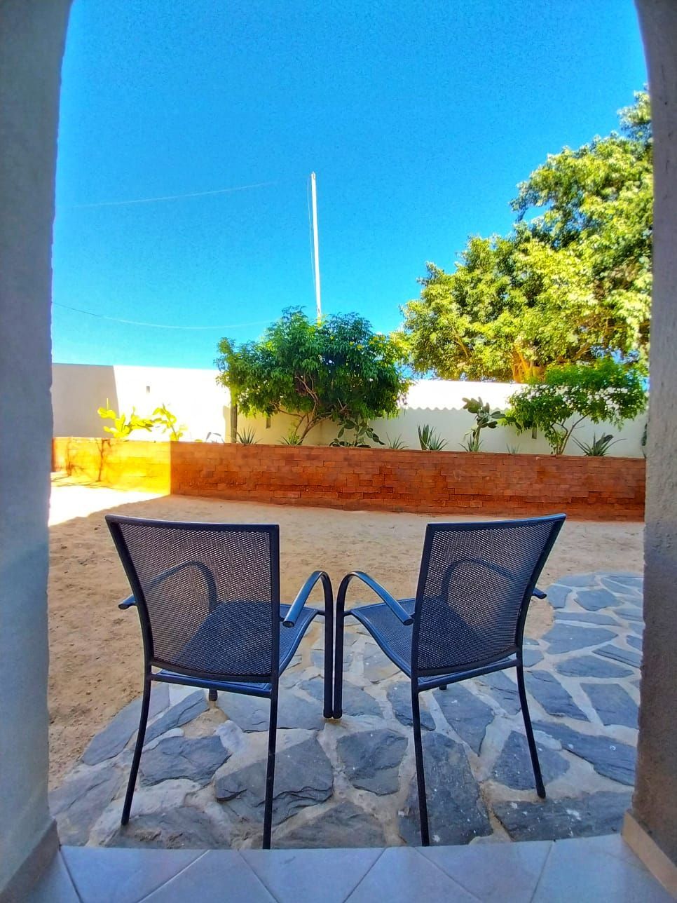 Two chairs are sitting on a patio with a blue sky in the background