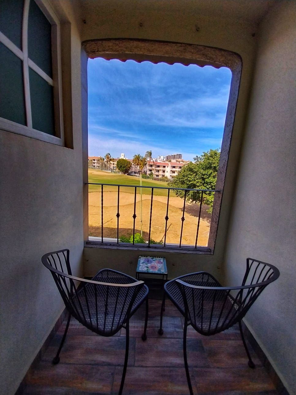 A balcony with two chairs and a table with a view of a golf course