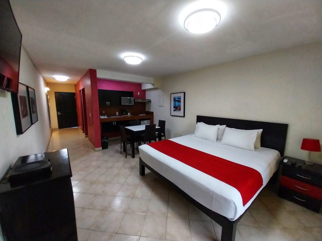 A hotel room with a king size bed and a red blanket