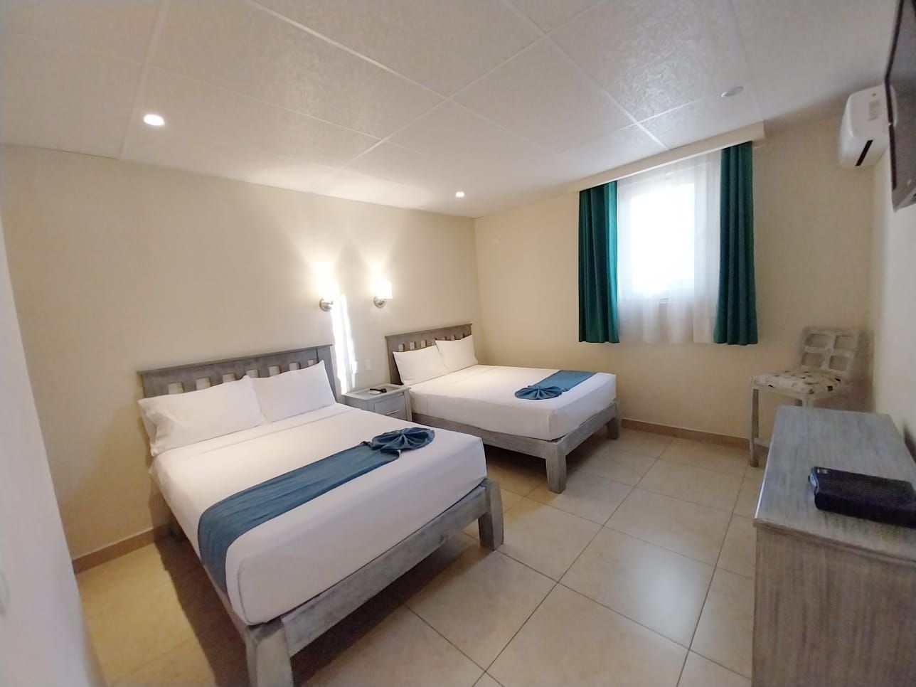 A hotel room with two beds and a dresser.
