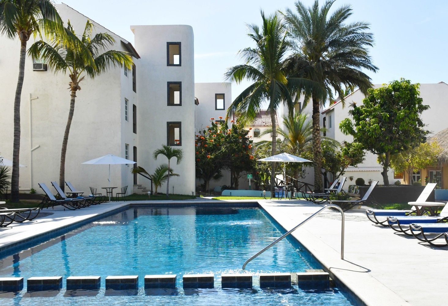 A large swimming pool in front of a building with palm trees