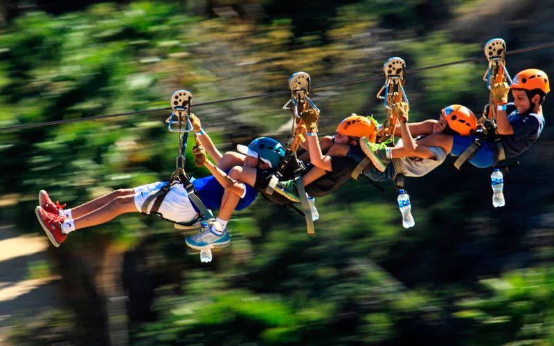 A group of people are flying through the air on a zip line.