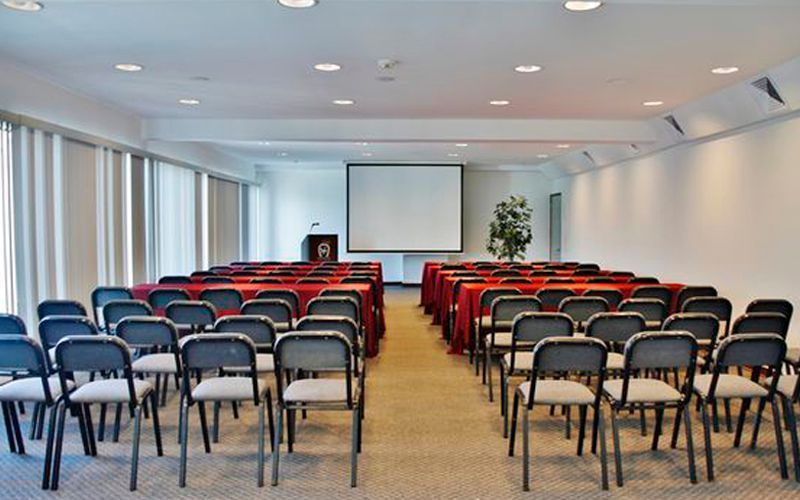 A conference room with rows of chairs and a projector screen.