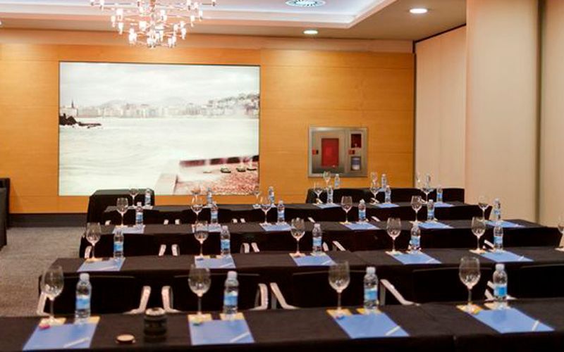 A conference room with tables and glasses set up for a meeting