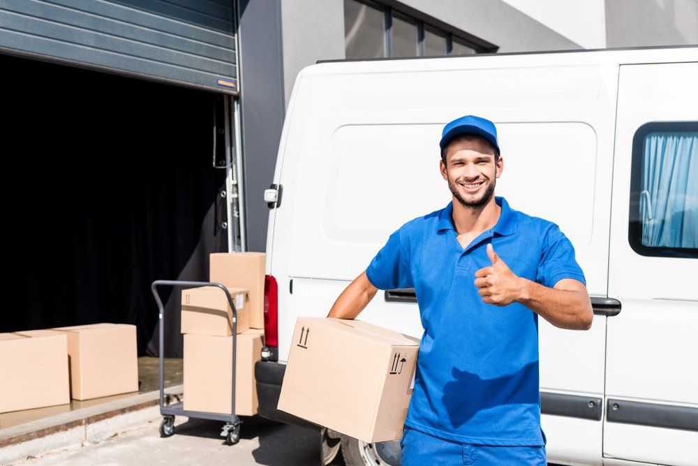 Smiling Delivery Man With Box Showing — Furniture Removalists in Burrum Heads QLD