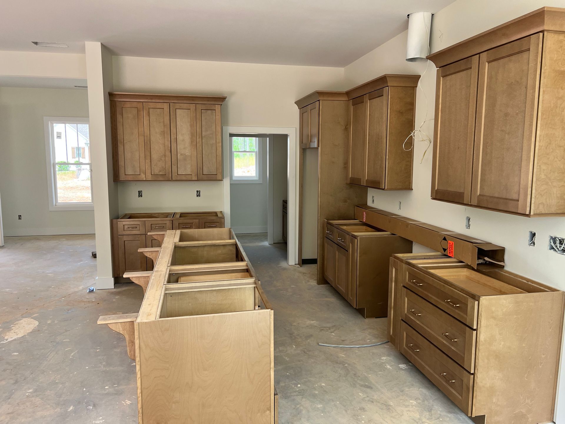 Kitchen under construction with unfinished wood cabinets and a central island.