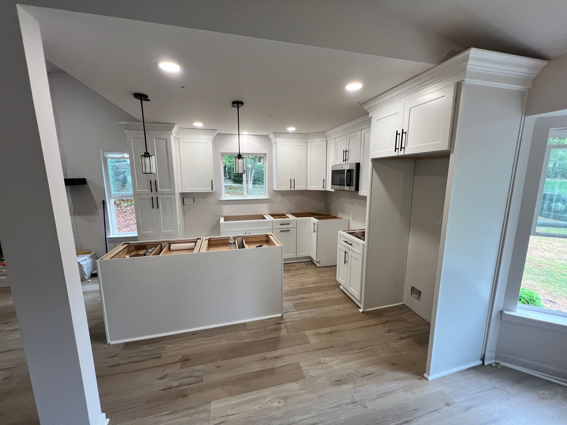 Newly renovated kitchen with white cabinets, island, and wood flooring.