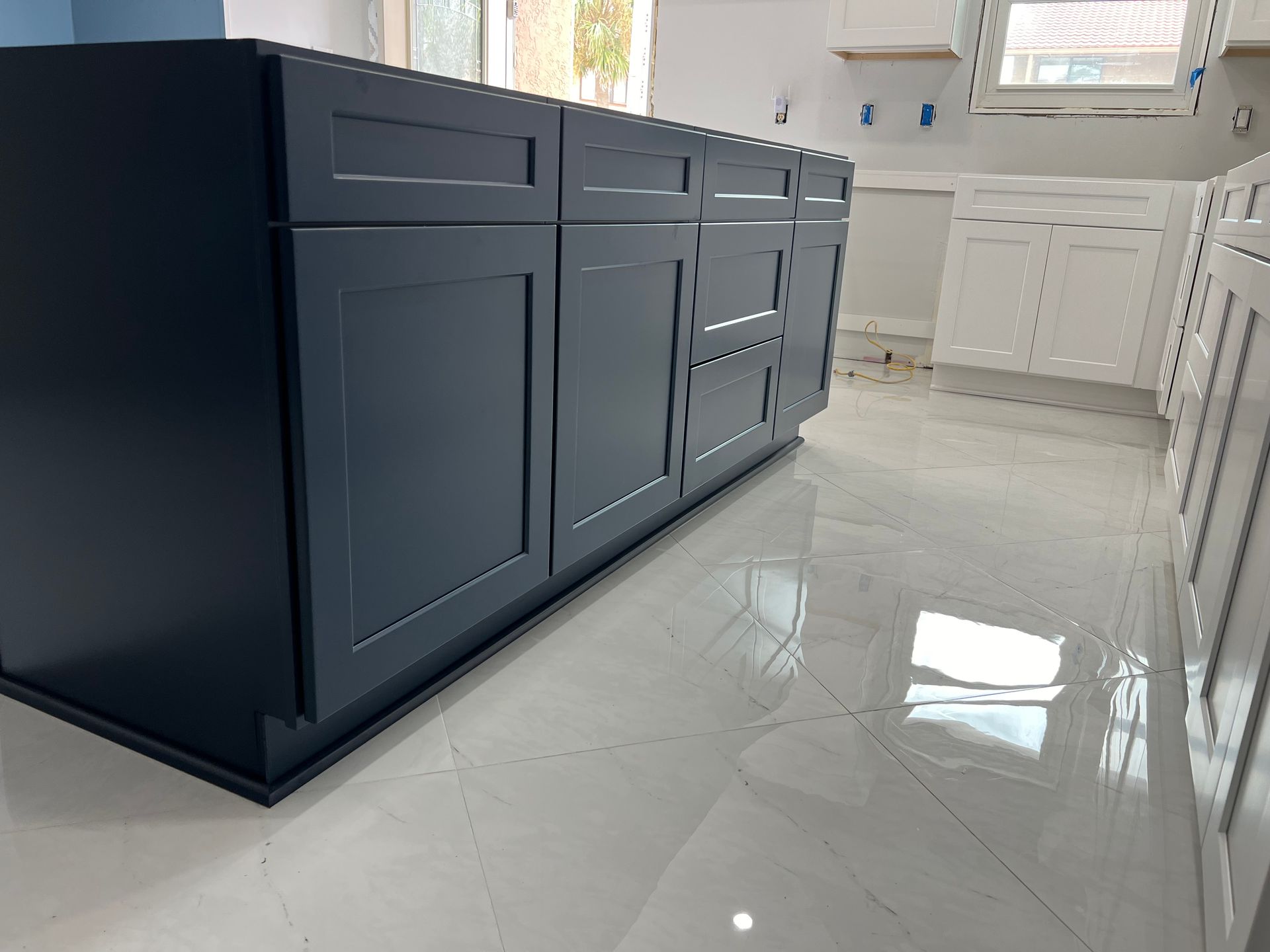 Dark blue kitchen cabinets on glossy white floor.