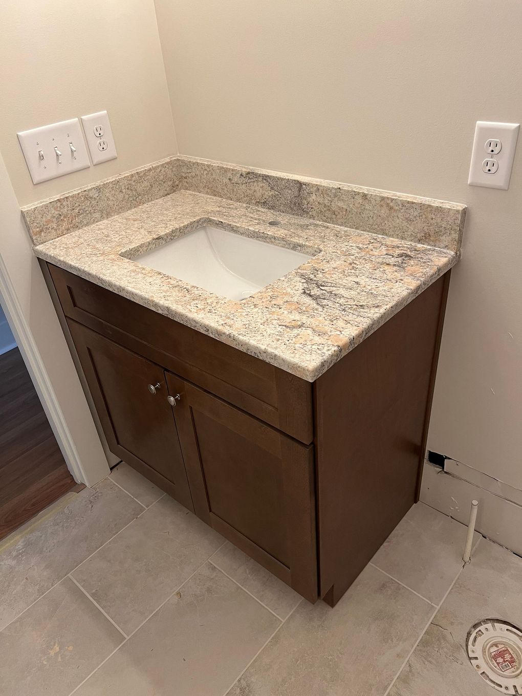 Bathroom vanity with a granite countertop and wooden cabinets.